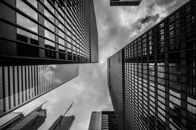 Office towers seen from street level against a cloudy sky